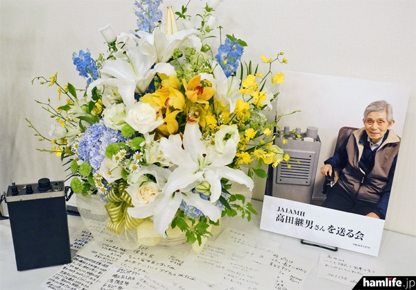 「JA1AMH 高田継男さんを送る会」会場に飾られた写真パネルと盛花