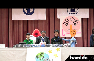 愛知県弥富市「弥生小学校（8N2YAYOI）」の会場では、イベントスタートに合わせ、「1分前」「しーー」といった手作りプラカードを持った子供たち